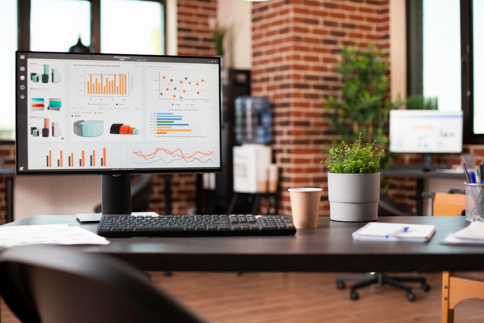 Escritorio profesional con dashboards de negocio en pantallas de oficina moderna.