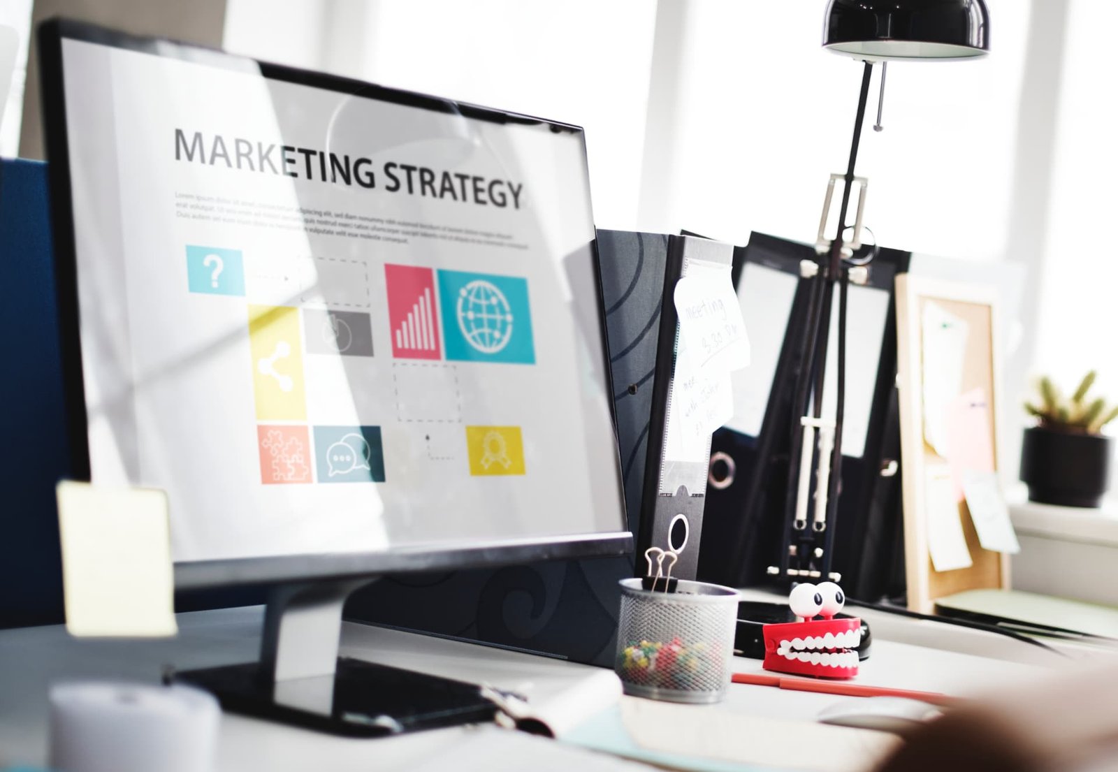Escritorio de trabajo con un tablero digital de estrategia de marketing en pantalla.